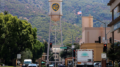 Warner Bros. water tower with WB logo in Burbank, California, surrounded by buildings, trees, and mountains in the background.